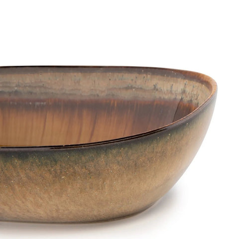A close-up of a ceramic bowl with an earthy brown, tan, and green gradient glaze highlights Portuguese ceramics, featuring a smooth, rounded rectangular shape and glossy finish, set against a white background.