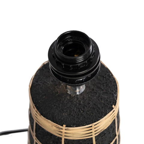 A close-up of The Naxos Table Lamp - Black Natural highlights its black base wrapped with tan rattan accents and an empty black light socket, with no bulb attached.