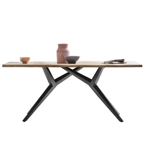 The Acacia Wood Table 160x85 cm features angled black metal legs and displays a pink cup, pink vase, gray bowl, and open magazine against a white background for an industrial style dining space.