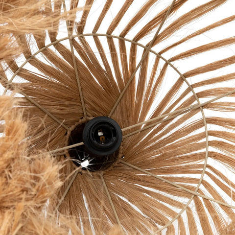 Close-up view of a rattan pendant light lampshade made from natural fibers, showing a circular metal frame and a black light bulb socket in the center. The woven fibers fan out radially around the socket.
