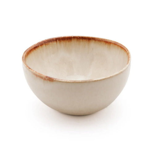 A cream-colored ceramic bowl with a smooth surface and a brown rim, this piece of handmade tableware draws inspiration from Portuguese ceramics, offering both elegance and chip-proof durability on a white background.