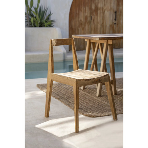 The Paxi Dining Chair - Natural - Outdoor features a handmade wooden minimalist design, placed on a woven rug by a wooden table near the pool, surrounded by modern natural decor.