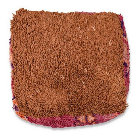 The Moroccan Floor Cushion is a square, brown cushion with a shaggy, textured design, accented by pink and purple edges and set against a white background.