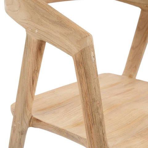 Close-up of an elegant dining chair showing smooth, light-colored wood with a natural grain, angled armrests, and a flat seat. The minimalist design appears sturdy and refined.