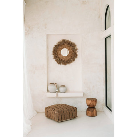 Nautical-themed room with decorative mirror, vases, wooden side table and ottoman.