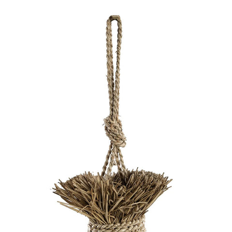 A close-up of a woven straw broom with a braided handle and large top knot, set against white, mirrors the artisanal feel of The Guagua Pendant - Natural - L, a handmade grass lamp.