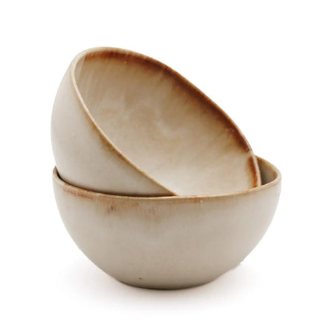 Two ceramic bowls with a light beige glaze and brown rim are stacked together on a white background, showcasing the timeless elegance of handmade tableware.
