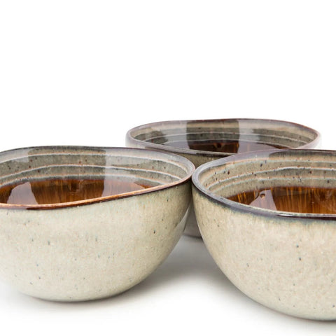 Three handmade ceramic bowls with a glossy brown interior and speckled, matte gray exterior are arranged closely together on a white background, showcasing the timeless beauty of Portuguese ceramics.
