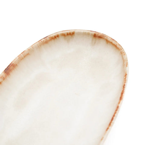 A close-up of a ceramic plate with a white surface and a brown, slightly uneven rim, showcasing handmade tableware inspired by Portuguese ceramics, set against a white background.