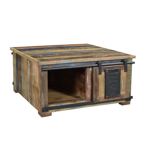 The Chest Coffee Table Patina is a square rustic coffee table made from recycled wood furniture, featuring multicolored planks, a sliding barn-style door on metal rails, and an open storage compartment.