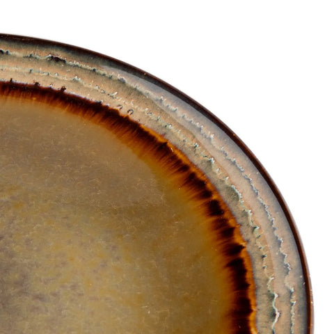 A close-up of The Comporta Dinner Plate - L - Set of 4 shows a textured, gradient rim in brown, beige, and blue with a crackle glaze finish and earth-toned colors that highlight its handmade style.