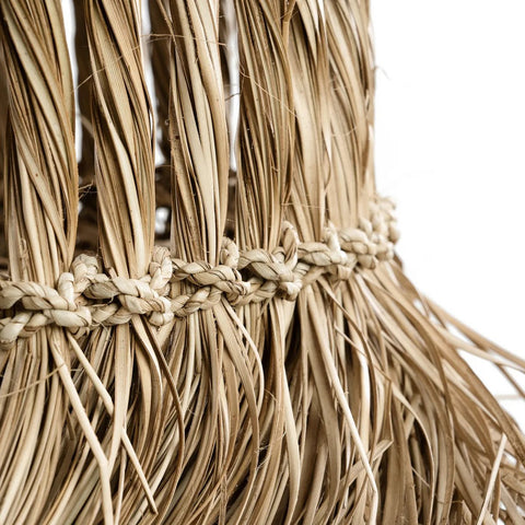 Close-up of The Guagua Pendant - Natural - L, handmade from woven straw or raffia with intricate knots, braids, and loose strands; set against a plain white background.