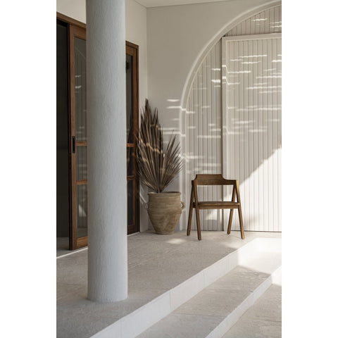 Modern interior with a wooden chair, plant, and white wall
