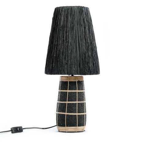 The Naxos Table Lamp - Black Natural features a textured black shade and matching base with a wrapped tan grid pattern, reminiscent of rattan. It includes a visible cord and switch, shown against a white background.