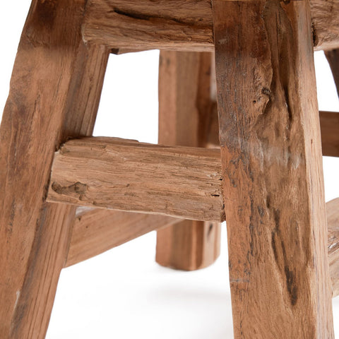 Close-up of a wooden stool with visible grain and texture on a white background