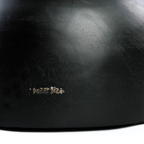 A close-up of a black suar wood surface with visible scratches and a small, faint inscription that reads Rozal Blaz near the bottom, showcasing the unique character of handmade furniture.