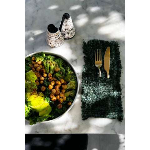 A bowl of food with fork and knife, served on unique tableware and accented by The Salt and Peppa Shell Set of 2 salt and pepper shakers.