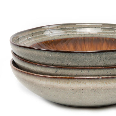 The Comporta Pasta Plate - L - Set of 4: Four stacked, round ceramic plates with a matte gray exterior, glossy brown interior, and subtle speckled patterns showcase rustic Portuguese craftsmanship against a white background.