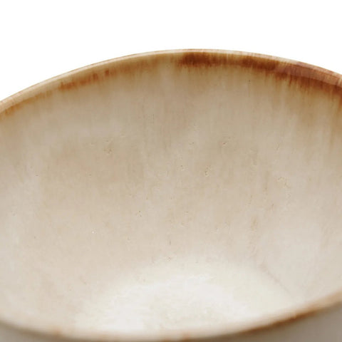 Close-up of the rim and inner surface of a beige ceramic bowl with a slightly uneven, brown-tinted edge, showcasing handmade tableware crafted from durable Portuguese ceramics, set against a white background.