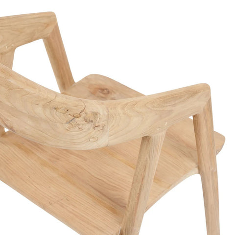 A close-up view of an elegant dining chair, showing the smooth curved backrest, angled armrests, and part of the seat, highlighting the natural wood grain and texture.