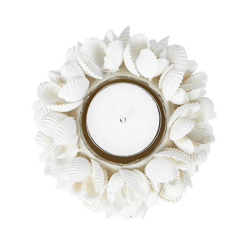 A boho-inspired tealight holder crafted with handmade shells, this white candle holder features a small, unlit tealight candle at its center. The seashells are artfully arranged in a circular, floral-like pattern for an enchanting touch.