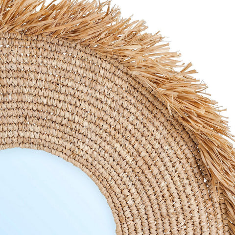 Close-up of a woven seagrass mirror with fringe on a white background