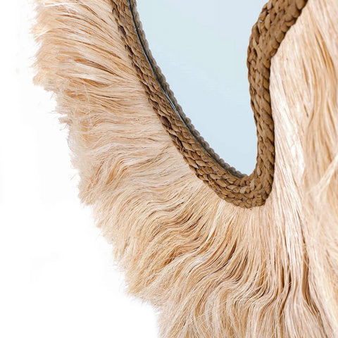 Close-up of a decorative mirror with frayed edge and woven frame 