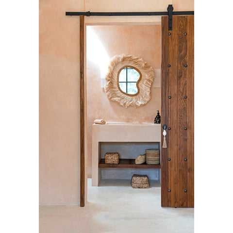 Bathroom with wooden sliding door, decorative mirror, and shelves.
