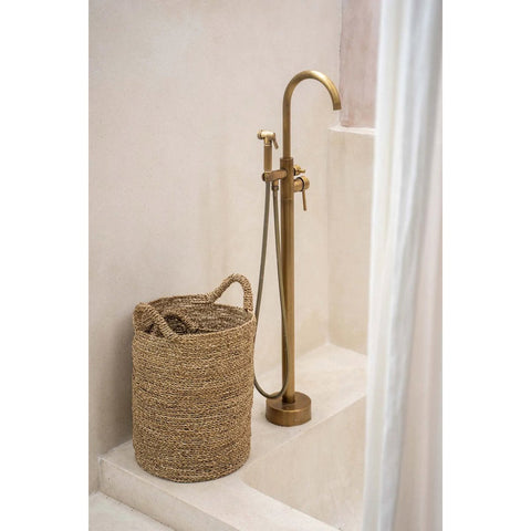 Brass shower faucet with a woven basket in a bathroom setting