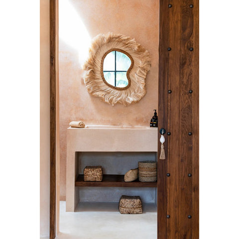 Bathroom with wooden door, round mirror, and decorative items.