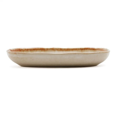 A shallow, oval ceramic plate with a beige glaze and subtle brown edging, expertly crafted as handmade tableware, shown from the side on a white background.