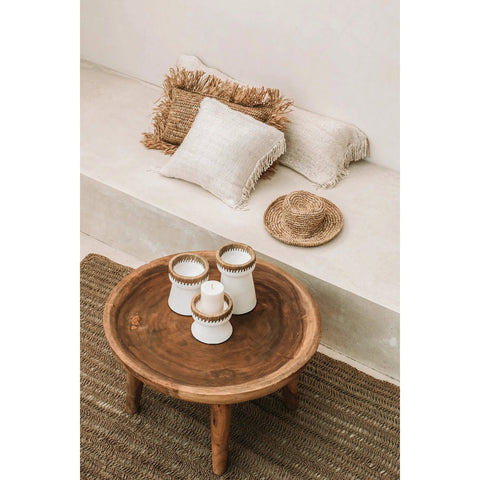 Wooden coffee table with decorative items on a rug in a cozy living room setting.