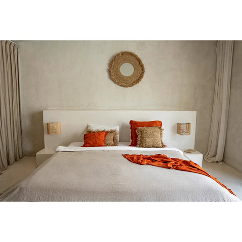 Neatly made bed with orange and beige pillows in a bedroom setting 