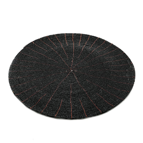 A circular, intricately hand-beaded black mat with thin red lines radiates a web-like pattern, capturing Boho Chic elegance. Its detailed, textured appearance against a plain white background makes it perfect for those who appreciate stylish beaded coasters.