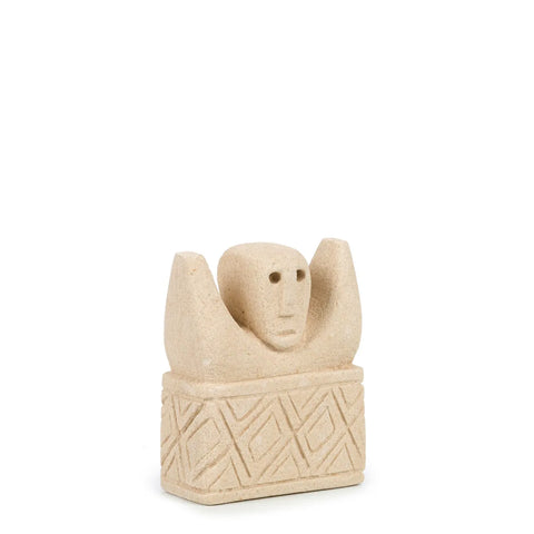 A beige stone sculpture of a human figure with raised arms, reminiscent of traditional village statues from Sumba, Indonesia. The piece features a stylized face and geometric patterns on the base, reflecting a minimalist, abstract design akin to hand-carved sandstone treasures.