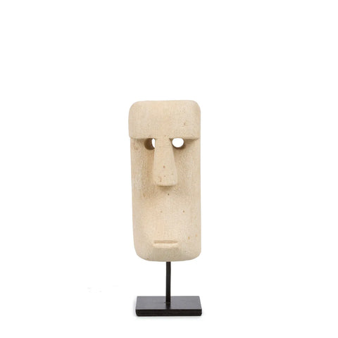 A minimalist stone sculpture resembling a Moai head from Easter Island, meticulously hand-carved from sandstone. Mounted on a black stand, the piece features elongated, simple details reminiscent of traditional Sumba Stone statues against a plain white background.