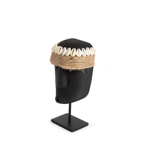 A black mannequin head showcases a headband made of brown twine adorned with white shells, reminiscent of the intricate designs found on hand-carved sandstone. It rests elegantly on a black stand against a plain white background.