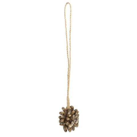 A decorative ornament resembling a pine cone, crafted from small golden seashells, with a long gold string for hanging. This handmade piece exudes a bohemian atmosphere with its textured, shiny appearance, perfect for enhancing holiday decorations or coastal home decor.