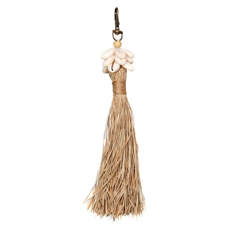 This handmade decorative tassel features a cluster of white shells at the top and is attached to a metal hook. Crafted from natural fibers, it exudes a bohemian atmosphere with its rustic appearance.