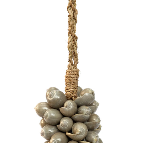 A cluster of spiraled seashells is intricately woven onto a braided rope, creating an exotic decoration suspended in mid-air against a white background. The shells have a glossy finish, perfect for infusing any space with a bohemian atmosphere.