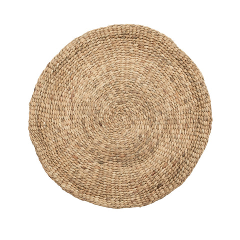 A round, woven jute placemat with a natural beige color. This Vietnamese home industry creation features a spiral pattern from the center outward, showcasing a textured and handcrafted design.