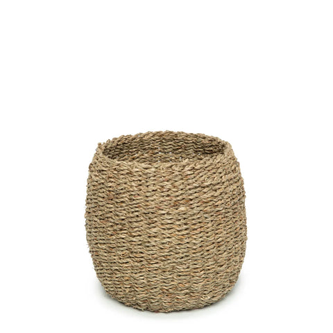 A round woven basket made of natural, earthy-toned fibers, set against a plain white background. The textured surface of this seagrass basket features an open top, making it perfect for storage or decorative purposes.