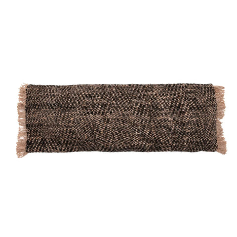 A rectangular brown and black patterned pillow with fringed edges on the sides exudes a boho vibe, nestled against a plain white backdrop.