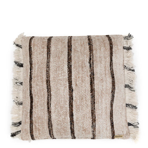 A square beige cotton cushion with brown and black vertical stripes and fringed edges exudes a boho vibe. The fabric features a textured, woven appearance.