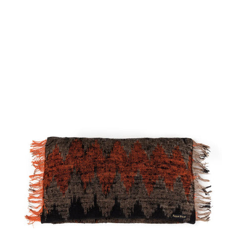 A handmade textile with a black and orange geometric zigzag pattern exudes a boho vibe, featuring fringed edges on the sides.