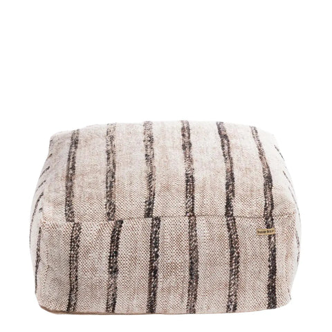 A square, woven cotton pouffe with textured beige fabric and vertical dark brown stripes. This seating element boasts a soft, cushioned appearance, making it an ideal home accessory for use as a footrest or extra seating in your living space.