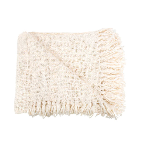 A luxurious, folded cream-colored blanket with a waffled structure and fringed edges, laid flat.