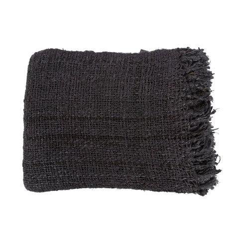 A folded black knitted blanket with a waffled structure and fringed edges exudes the charm of luxury hand-woven cotton plaid.