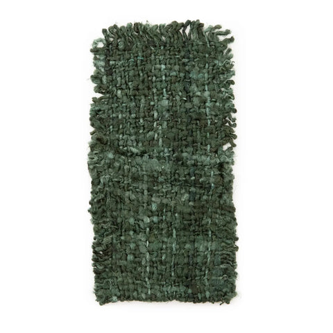 A rectangular, textured green rug with a thick, woven design complements any luxury dining table. Its surface is soft and slightly shaggy, offering a cozy and handcrafted appeal as a unique textile product.