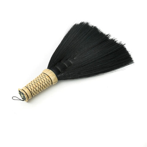 Bamboo handle with black bristles forms a traditional Indonesian hand sweeper, isolated on a white background, offering a Boho charm to your sweeping routine.